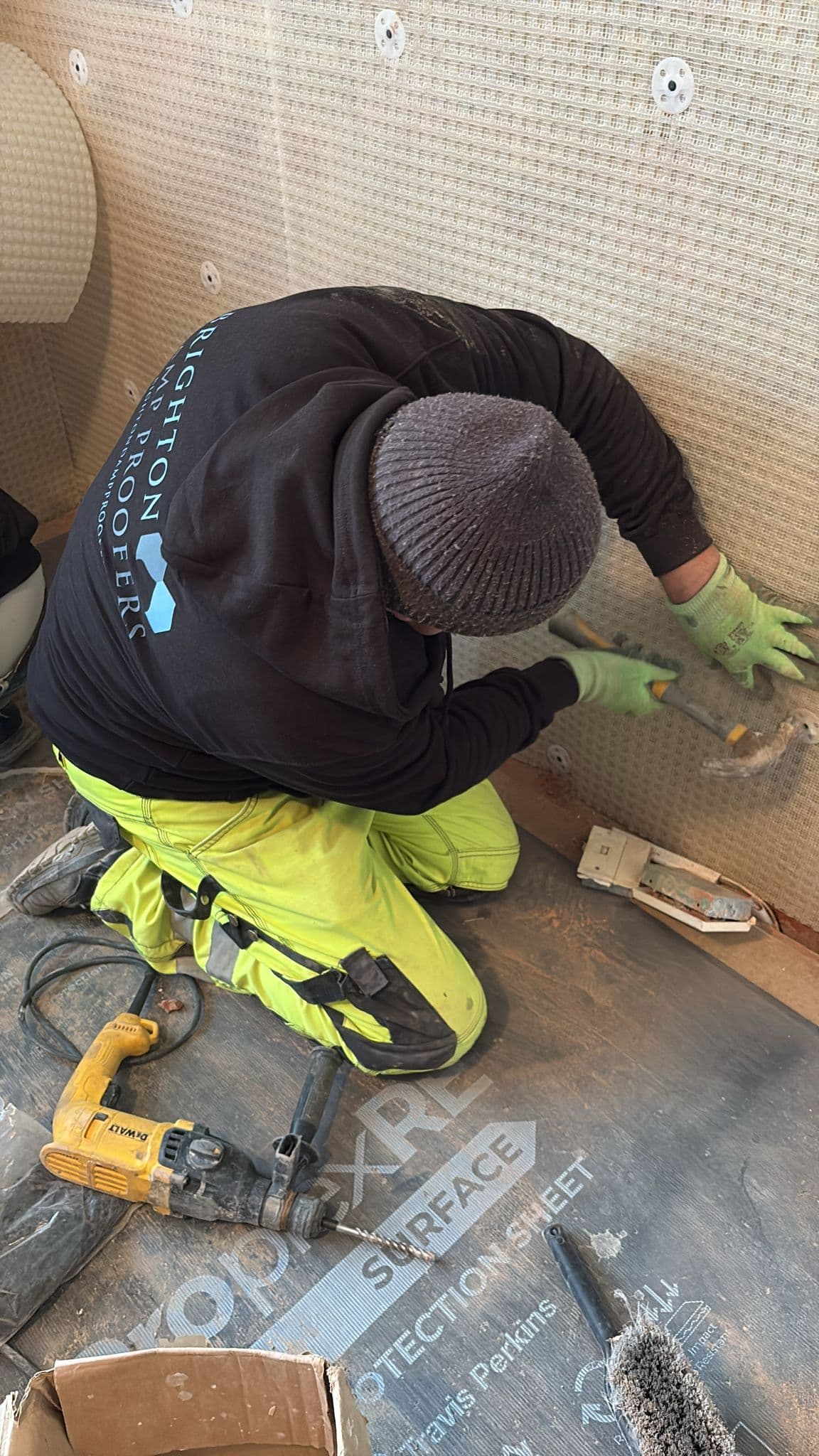 A Brighton Damp Proofers fitter fixing a studded cavity drain membrane to a wall with sealed plugs