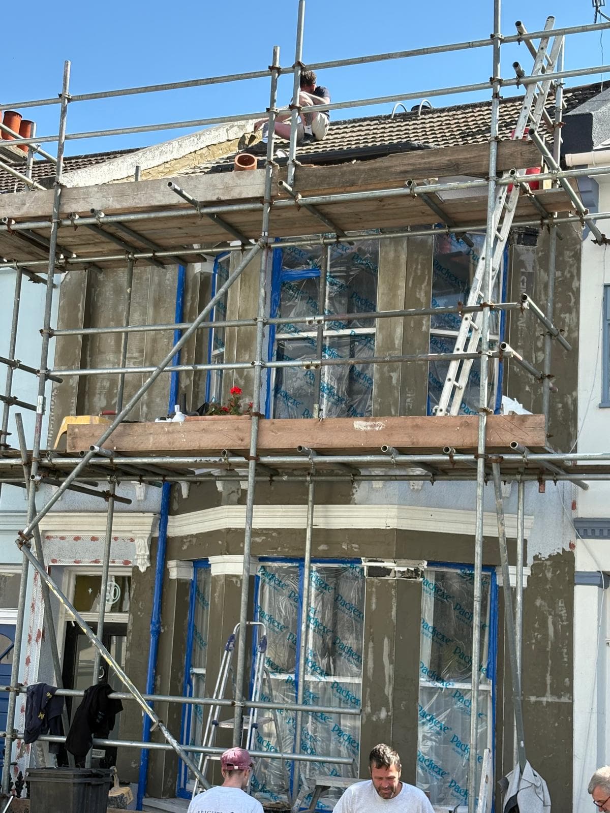 Brighton Damp Proofers team re-rendering the front elevation of a bay-fronted Victorian terrace under full scaffold