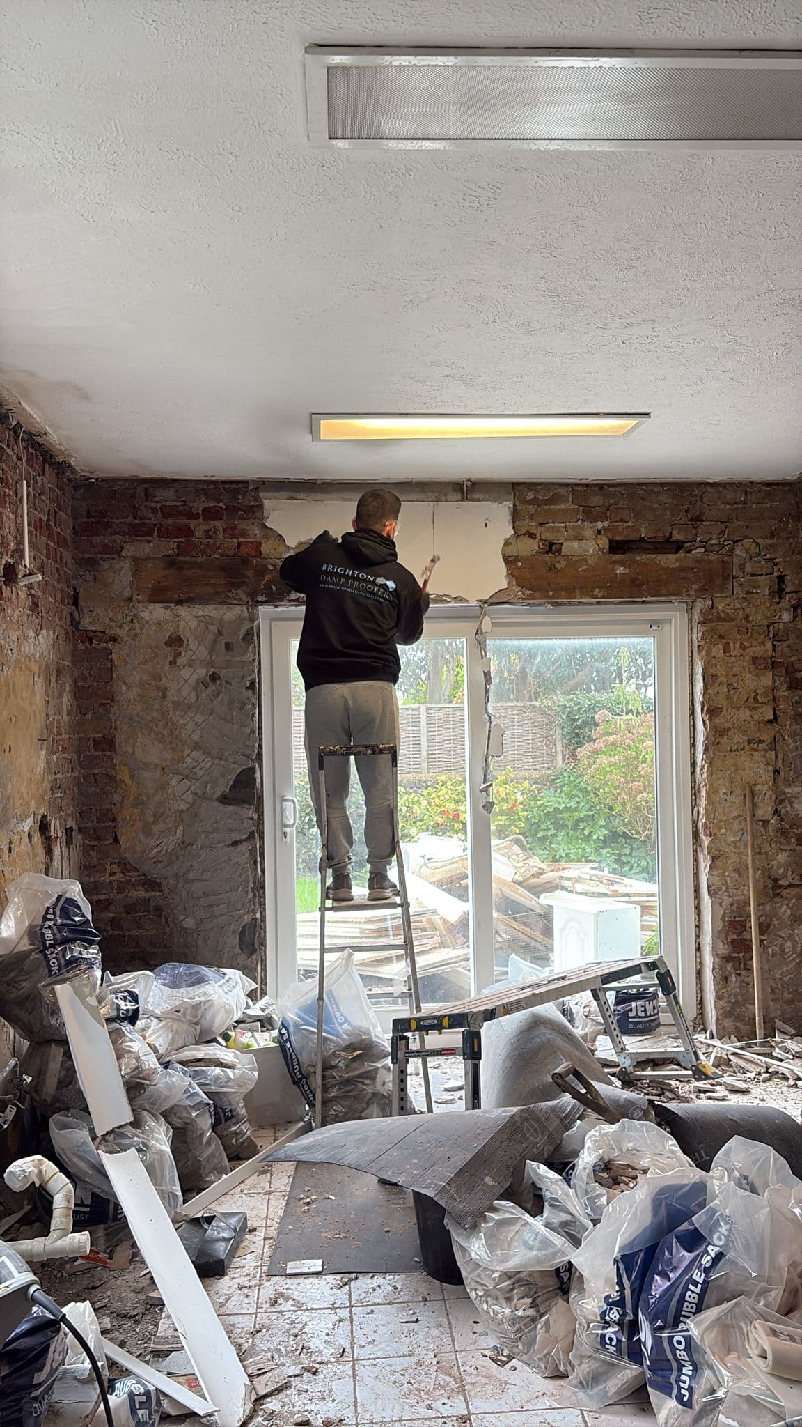 A Brighton room stripped back to bare brick and stone, old plaster and skirtings removed ready for damp treatment